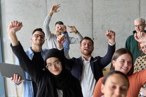 A diverse team of business professionals ecstatically celebrating their success in a modern office, expressing triumph and unity after achieving their goals photo