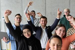 A diverse team of business professionals ecstatically celebrating their success in a modern office, expressing triumph and unity after achieving their goals photo