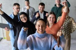 A diverse team of business professionals ecstatically celebrating their success in a modern office, expressing triumph and unity after achieving their goals photo