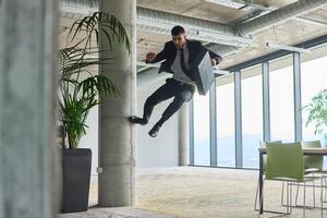 A businessman ecstatically jumping in a modern office, holding a briefcase in his hands, celebrating a moment of success and triumph. photo