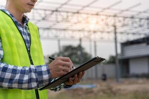 inspector or engineer is inspecting construction and quality assurance new factory using a checklist. Engineers or architects or contactor work to build the factory before handing it over photo