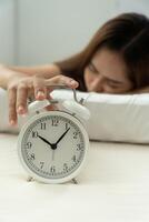 Lazy Asia young woman close a clock alarm, lady is late appointment or work or class study, overslept, difficulty get up in mornings, time worried, not on time, sleepy, over due, Hurry up time photo