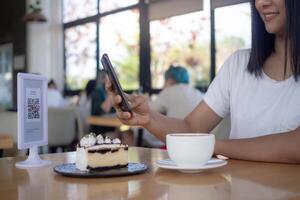 Woman use smartphone to scan QR code for order menu in cafe restaurant with a digital delivery. Choose menu and order accumulate discount. E wallet, technology, pay online, credit card, bank app. photo