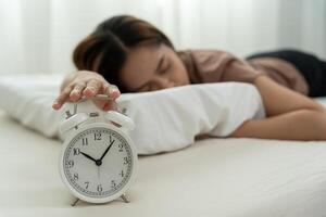 Lazy Asia young woman close a clock alarm, lady is late appointment or work or class study, overslept, difficulty get up in mornings, time worried, not on time, sleepy, over due, Hurry up time photo