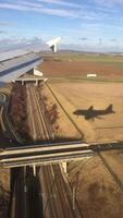 A plane flying over a field with a shadow photo