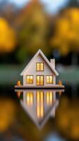 A serene miniature house model reflected on water with warm lights and autumn backdrop. photo