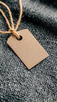 Blank brown paper tag on a textured fabric background. photo