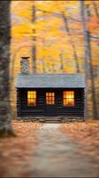 Charming cabin illuminated at dusk surrounded by vibrant autumn trees. photo