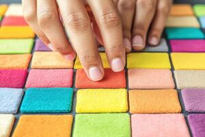 Colorful tiles arranged in a mosaic pattern with human hands interacting with them. photo