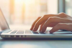 Close-up of hands typing on a laptop in a bright, modern workspace. photo
