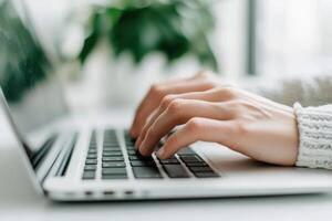 Close-up of hands typing on a laptop keyboard in a modern office setting. photo