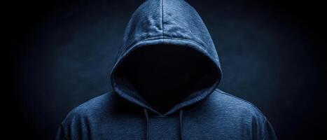 A mysterious figure in a hoodie, face hidden in shadows, symbolizing anonymity. photo