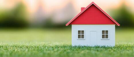A small model house on green grass with a blurred background, symbolizing home and comfort. photo