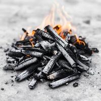 Burning charcoal with glowing embers and smoke on a surface. photo