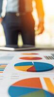 A businessman analyzing colorful pie charts on a desk in a bright office setting. photo