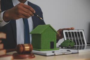 Auctioneer knocks down property sale by sample house and lawyer's gavel, judge mediates in property dispute in court car judge's gavel on wooden background Buying and selling real estate, housing photo