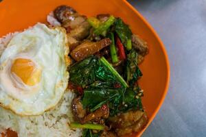 Stir fried kale with crispy pork served with rice and egg photo
