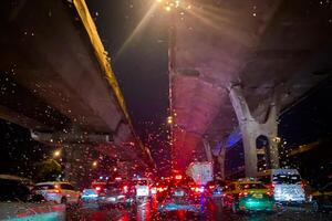 Trafic jam under expressway in city while its raining and and droplets on the windshield at Thailand. photo