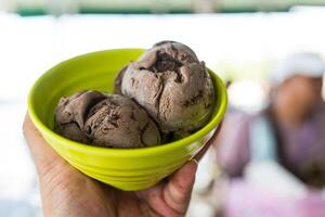 Scoop of chocolate ice cream in green bowl. photo