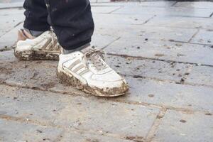 Sneakers Covered in Dirt Resting on a Paved Surface After an Outdoor Activity photo