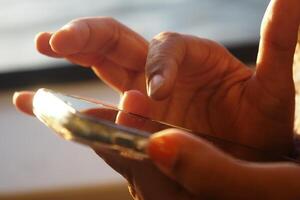A CloseUp View of Hands Engaged in Using a Smartphone in Natural Light photo