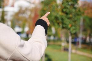 A person is enthusiastically pointing towards the trees in a lovely park photo