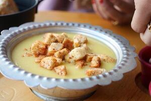 delicioso cremoso sopa con picatostes en metal cuenco en de madera mesa foto