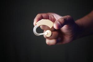 A Hand Holding a Hearing Aid Device for Improved and Enhanced Auditory Assistance Needs photo