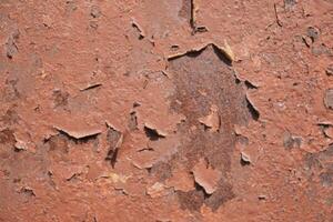 An ancient and weathered red surface exhibiting flaking paint and a rich texture throughout photo