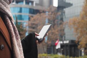 A person is engaged in using a smartphone while outdoors in an urban environment setting photo