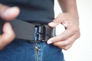 Making adjustments to a belt on a stylish pair of jeans for a perfect, comfortable fit photo