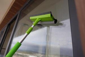 Rubber squeegee cleans a soaped window. photo