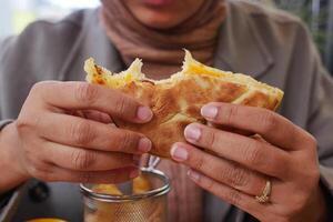 A CloseUp of Hands Enjoying a Delicious Savory Flatbread Topped with Melted Cheese photo