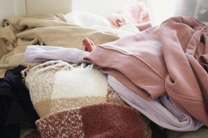 A Cozy Pile of Warm Clothing is Neatly Arranged on a Comfortable Bed for Relaxation photo