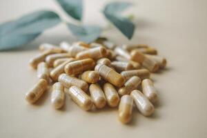 top view of herbal capsule supplement dropping on table photo