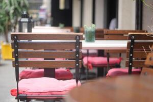Charming and Inviting Outdoor Cafe Seating Featuring Wooden Chairs and Soft Cushions photo