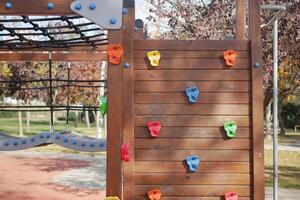 A bright and colorful climbing wall can be found at a playground, perfect for kids to enjoy photo
