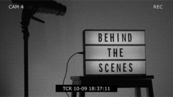 Behind the scene light box in front of vdo camera frame. Black text on white lightbox of word Behind the scenes. Prop for filmmaker movie or film studio. Footage for B roll film production making of. video