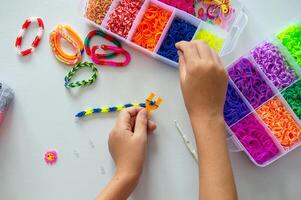 Crafting Colorful Loom Bracelets with Rainbow Bands on White Surface photo