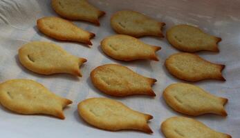 A straw bread box lined with a clean napkin and rows of baked cookies in a fish form closeup photo