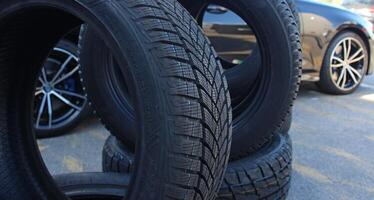 Variety stacked tires in front of the car wait for tire changes service. Vehicle stand behind pile of tires at car workshop photo