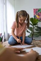 Charming little girl drawing with colorful felt pens in her album at her grandmother's house photo