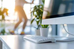 Desk setup with computer, keyboard, plants on blurred background of an active figure photo
