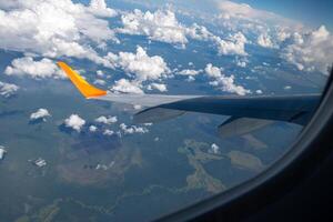 View from airplane window on wing and landscape with clouds on window during flight. photo