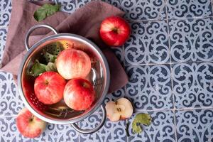 Ripe red apples lie in a metal colander on a table . photo