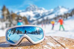 Ski goggles on a wooden table, reflecting a snowy scene with skiers photo