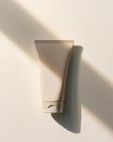 A light brown plastic hand cream tubes on beige background with soft shadow packaging mockup Generated Image photo