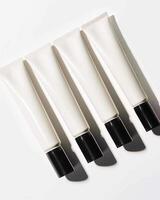 Four tubes of hand cream with black cap on a white surface photo