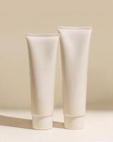 Two white plastic tubes of hand cream on a beige background photo