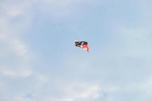 Colored paper kite like rainbow on blue sky background. Kites are flown along the beach. Beautiful colors in the air photo